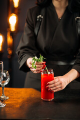 Young woman making bloody mary cocktail garnished with celery