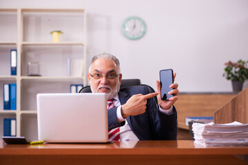 Old male employee sitting in the office