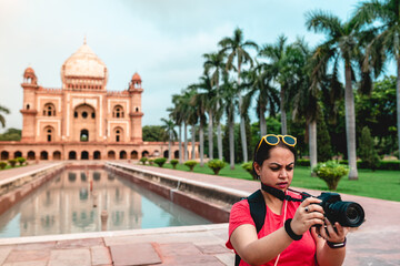 A tourist photographer girl shooting a video using neck strap for stability at the famous Indian travel destination. Safdarjung tomb, a historical mughal monument in Delhi, India