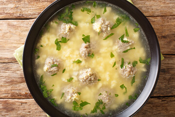 Sciusceddu or Italian Meatball and Egg Soup, is a popular, beef broth based soup served traditionally during Easter celebrations closeup in the plate on the table. horizontal top view from above