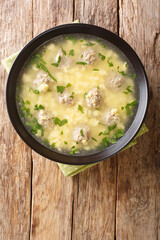 Italian Sciusceddu meatballs and egg soup closeup in the plate on the table. vertical top view from above