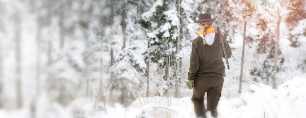 A young hunter woman on the hunt in the forest. She have reflective elements on hunting clothes and...