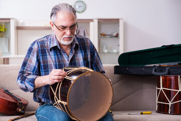 Senior male repairman repairing musical instruments at home