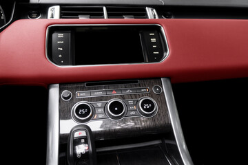 Fototapeta na wymiar Red luxury modern car Interior. Shift lever and dashboard. Detail of modern car interior. Automatic gear stick. Part of leather seats with stitching in expensive car