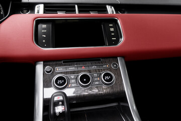 Fototapeta premium Red luxury modern car Interior. Shift lever and dashboard. Detail of modern car interior. Automatic gear stick. Part of leather seats with stitching in expensive car