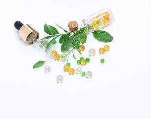 pipette and Capsules of various vitamin and green plant leaf on white background. pharmaceutical capsules, fish oil, vitamins A, D, medical eco care. 