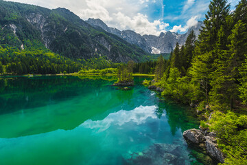 Fototapeta na wymiar Spectacular lake Fusine with green forest and high mountains, Italy