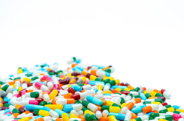 Selective focus on pile of multi-colored antibiotic capsule pills. Antimicrobial capsule pills on white background. Antibiotic resistance concept. Pharmacy drugstore products. Pharmaceutical industry.