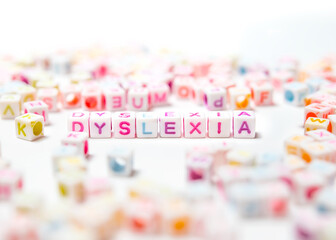 Dyslexia spelled in colorful block letters, perspective view. Selective focus on Dyslexia with blurred and defocused letter in foreground and background.