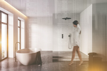 Woman walking in white bathroom with tub and shower