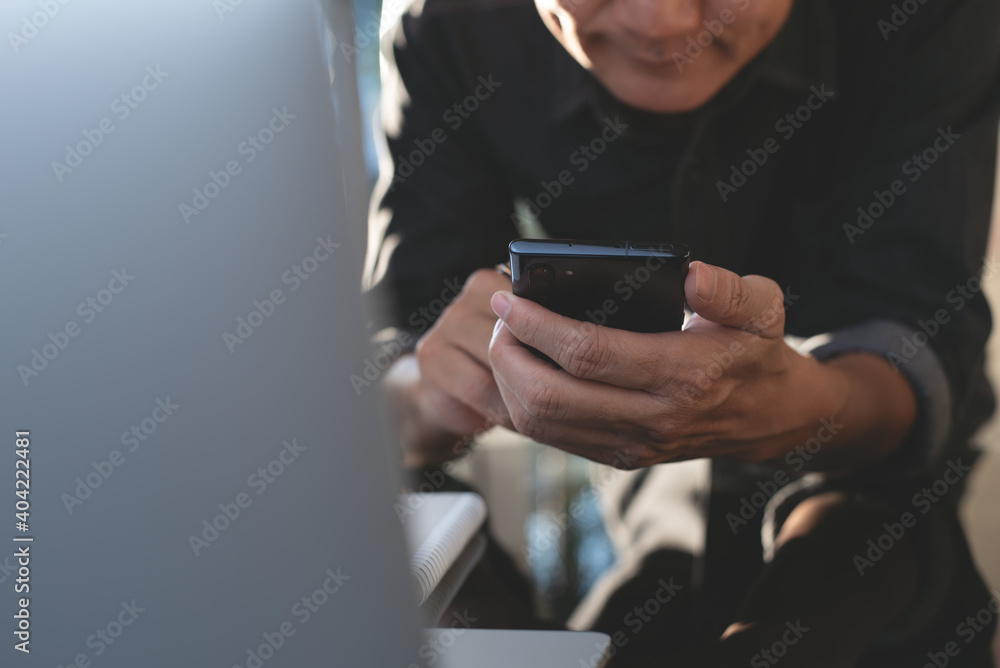 Poster man using mobile phone video calling during working on laptop computer in office