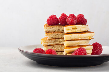 Cuted stack of fluffy pancakes with raspberries. On light table and white background. Close-up. Copy space.