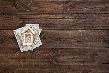 Obraz na płótnie Canvas toy wooden house with dollars on old wooden background