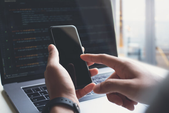 Mockup of man using and pointing at blank screen mobile phone during working at office
