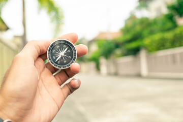 Man hand holding compass on city and car blurred background Using wallpaper or background travel or navigator image.