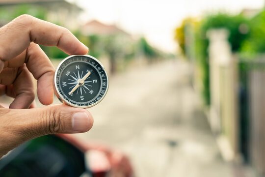 Man hand holding compass on city and car blurred background Using wallpaper or background travel or navigator image.