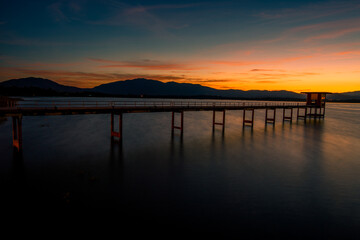 Obraz premium The background of the bridge stretches into the sea, with twilight light in the morning, beautiful colors, sky wallpaper and refreshing surroundings.