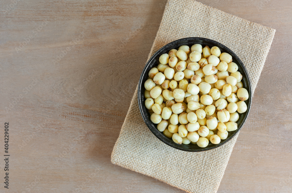 Wall mural top view of vacuum fried lotus seeds in a ceramic bowl on wooden table. healthy food concept.