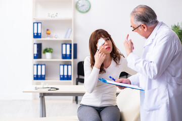 Young woman visiting old male doctor ophthalmologist