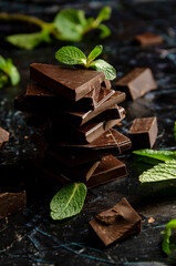 stack of chocolate pieces with a leaf of mint on dark