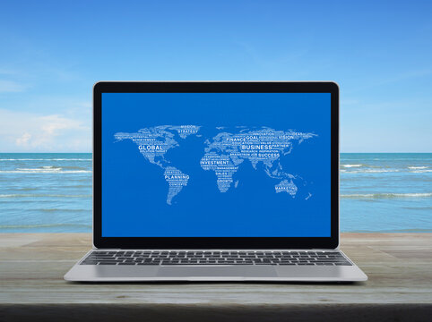 Global business words world map with modern laptop computer on wooden table over tropical sea and blue sky with white clouds, Global business online concept, Elements of this image furnished by NASA