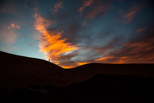 Un uomo da solo sulla duna a vedere sorgere il sole nel deserto del Marocco