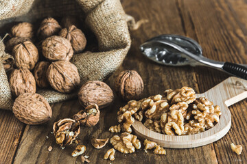 Whole and peeled walnuts on a rustic wooden table, focus on the walnut kernels