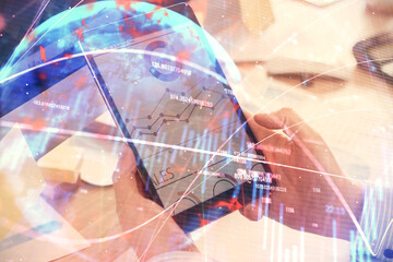 Double exposure of man's hands holding and using a phone and financial graph drawing. Analysis concept.