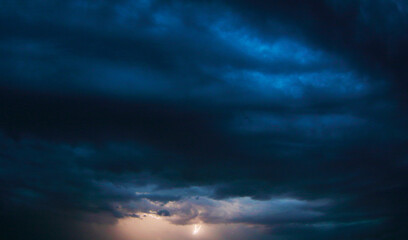 Naklejka na ściany i meble Stormy sky during a thunderstorm. Thunderous flash on the horizon of a dark blue sky. For background wallpapers and postcards.