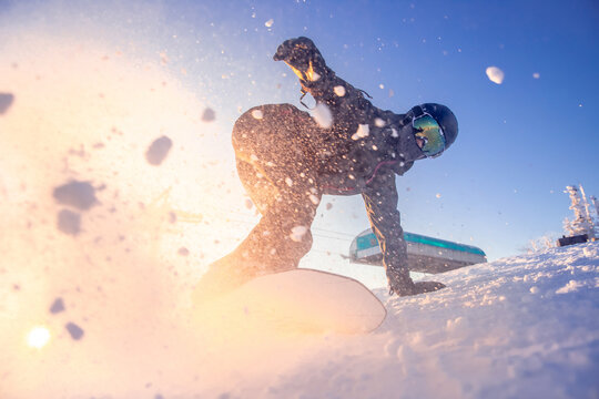 Snowboarder woman on snowboard rides through snow explosion. Freeride snowboarding in Sheregesh Ski Resort