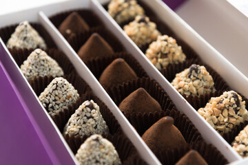 In the box are rows of different chocolates. A gift or greeting. Festive dessert.