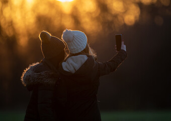 Teenage girls taking selfie in park in winter time
