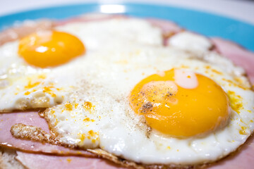 Closeup of a meat sandwich with fried egg. Yellow egg yolk.
Dutch lunch Uitsmijter.