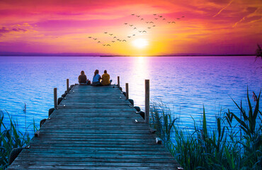 Fototapeta na wymiar personas en vacaciones mirando la puesta de sol en el embarcadero