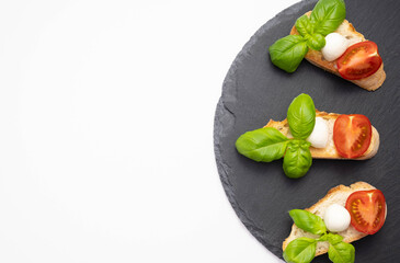 on a stone stand croutons on them mozzarella, fresh basil and chopped tomatoes