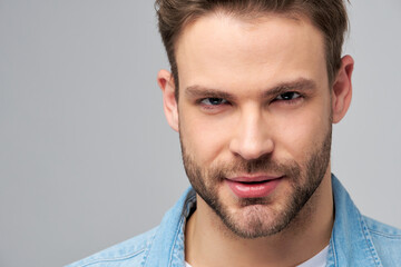 Fototapeta premium Close-up Portrait of young handsome caucasian man in jeans shirt over light background
