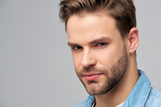 Close-up Portrait of young handsome caucasian man in jeans shirt over light background