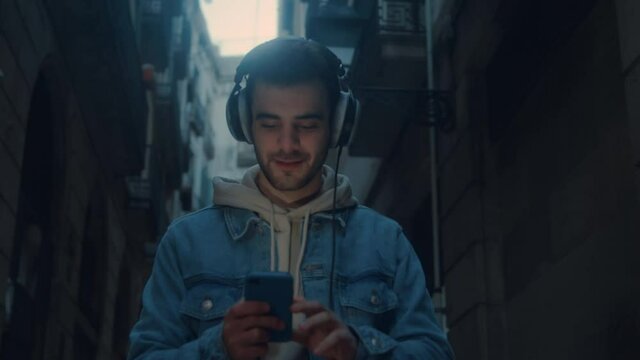 Handheld video of handsome stylish millennial man in casual outfit listen to podcast hipster music track on audio streaming application. Generation z technology integration in daily life. Sound check