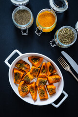 Roasted spicy pumpkin with feta cheese on black table 
