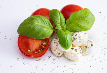 mozzarella with tomatoes and basil sprinkled with spices and dressings on a white table