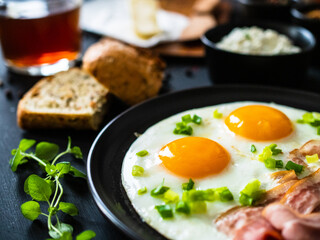 Continental breakfast - sunny side up eggs on bacon on wooden table