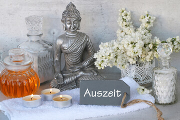 Fototapeta na wymiar Buddha mit Spa-Produkten und einem Label mit der Inschrift Auszeit