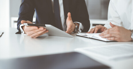 Unknown business people using tablet computer in modern office. Businessman or male entrepreneur is working with his colleague at the desk