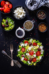 Fresh Greek salad - feta cheese, tomatoes, cucumber, lettuce, black olives and onion on wooden table