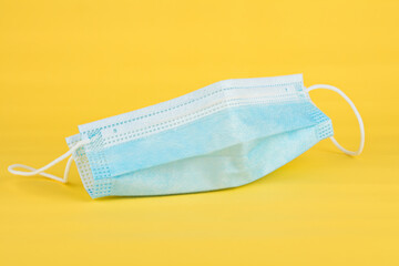 Antibacterial medical mask of blue color on a yellow background virus epidemic coronavirus protection