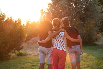 Famiglia composta da tre persone , di spalle ,si abbraccia in segno di unione rivolti verso il...