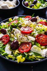 Fresh Greek salad - feta cheese, tomatoes, cucumber, lettuce, black olives and onion on wooden table