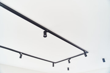 Modern LED black track spot lights in the interior. Hanging lamps spotlights attached to a concrete...
