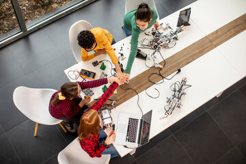 Happy kids programming electric toys and robots at robotics classroom