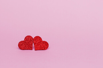 Two glitter shiny  red  hearts on pink background. Copy space.  Valentine's day background